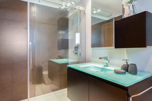 A modern bathroom with a glass shower enclosure, a glass sink, and a dark wooden vanity. - Snazzy Varandas do Castelo One-bedroom Apartment Sleeps 2 Person (Albufeira)