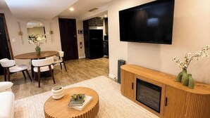 A modern living room with a flat-screen TV, a round coffee table, and a fireplace. - Sleeps 26 • Modern Multi-Unit • Gym • Workspaces (Chicago)
