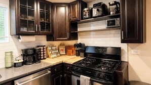 A modern kitchen with dark cabinetry, stainless steel appliances, and a wooden countertop. - Sleeps 26 • Modern Multi-Unit • Gym • Workspaces (Chicago)