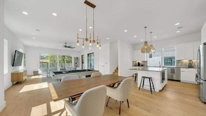 A modern kitchen with a central island, wooden flooring, and pendant lighting. - Luxury Pool Retreat, Game Room, Sleeps 24 (Austin)