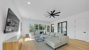 A modern living room with a sectional sofa, a coffee table, and a TV mounted on the wall. - Luxury Pool Retreat, Game Room, Sleeps 24 (Austin)
