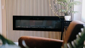 Un saló amb una llar de foc moderna, una cadira de cuir marró i una planta en test.