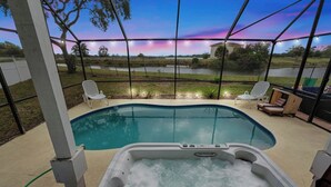 Zwembad met een jacuzzi, omringd door een overdekt terras met stoelen en lichtjes.
