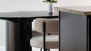 A modern dining area with a dark wooden table, a vase with flowers, and a wall-mounted abstract art piece. - 2BR • Newly Furnished Modern Apt • Near O'Hare (Chicago)
