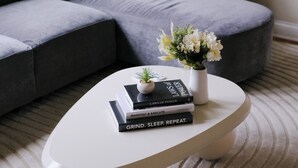 Ein modernes Wohnzimmer mit einem grauen Ecksofa, einem weißen Couchtisch und einem kleinen Topfpflanzen.