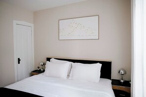Una habitación de hotel con una cama, una mesita de noche, una lámpara y un cuadro colgado en la pared.