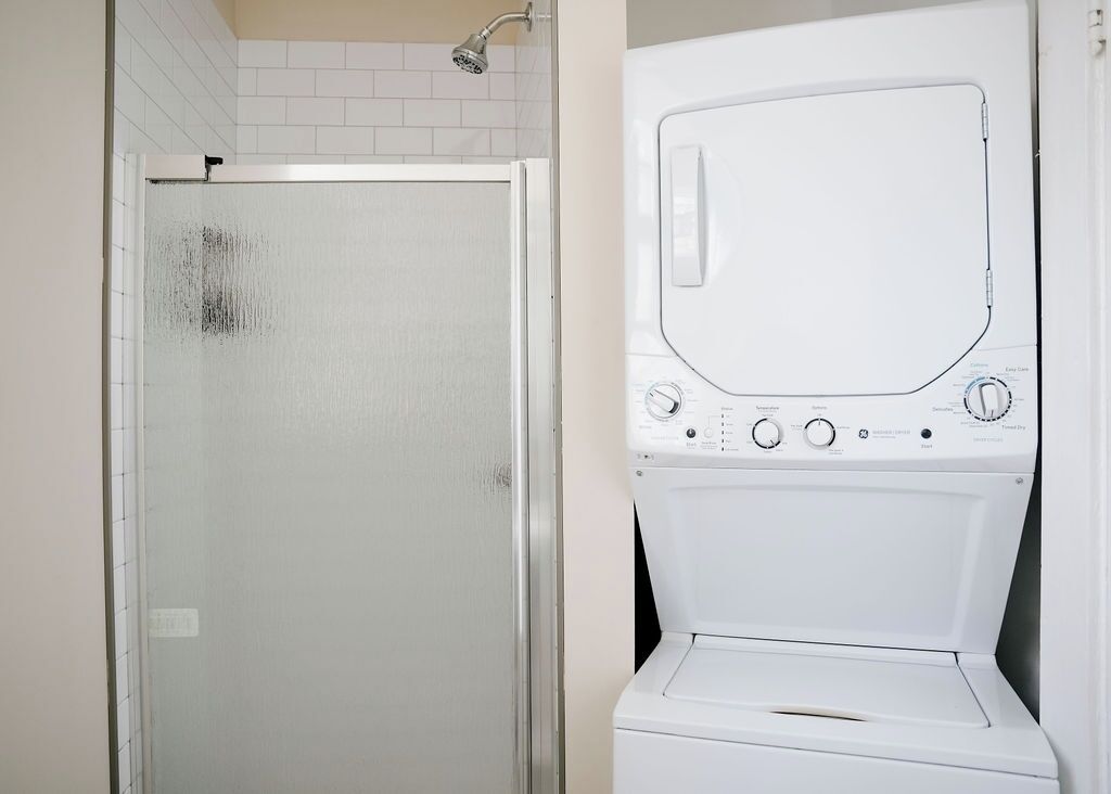 Un bagno con box doccia in vetro e una lavatrice bianca.