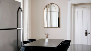 Eine moderne Küche mit einem Edelstahl-Kühlschrank, einem Esstisch mit Stühlen und einem an der Wand befestigten Spiegel.