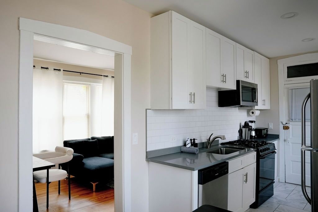 A modern kitchen with white cabinets, a black stove, and a microwave.