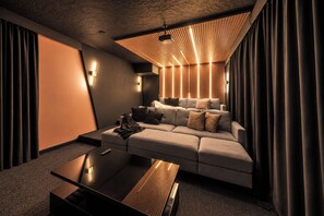 A modern living room with a sectional sofa, a coffee table, and a ceiling projector. - Heated Pool • Sleeps 25 • Pickle/Bball • Theater (Bradenton)