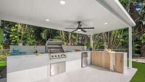 Una cocina exterior con estufa a gas, horno empotrado y refrigerador.