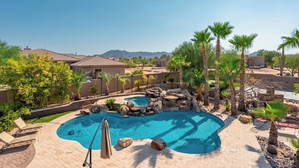 A backyard with a swimming pool, palm trees, and a mountain view. - Sleeps 25 • Heated Pool and Spa • Pickleball Court (Scottsdale)
