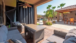A covered outdoor seating area with wicker furniture, a wooden table, and a ceiling fan. - Sleeps 25 • Heated Pool and Spa • Pickleball Court (Scottsdale)