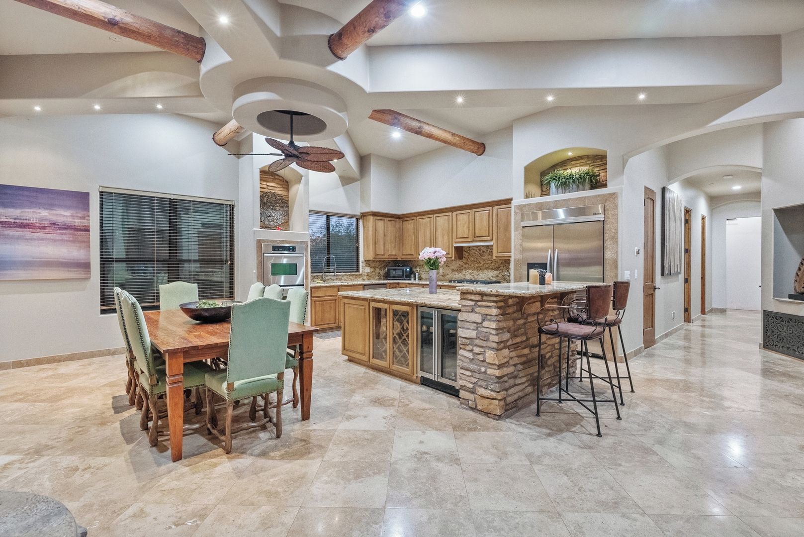 A spacious kitchen with a central island, wooden cabinets, and a stone accent wall.