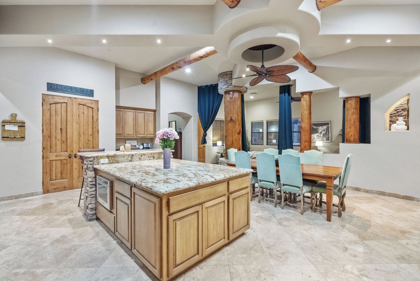 A spacious kitchen with a central island, wooden cabinets, and a dining area with a table and chairs.