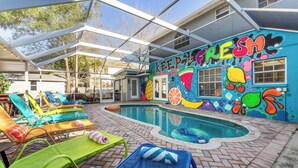 A pool area with colorful lounge chairs and a mural on the wall. - Sleeps 25 • Heated Pool• In+Outdoor Games •Theater (Tampa)