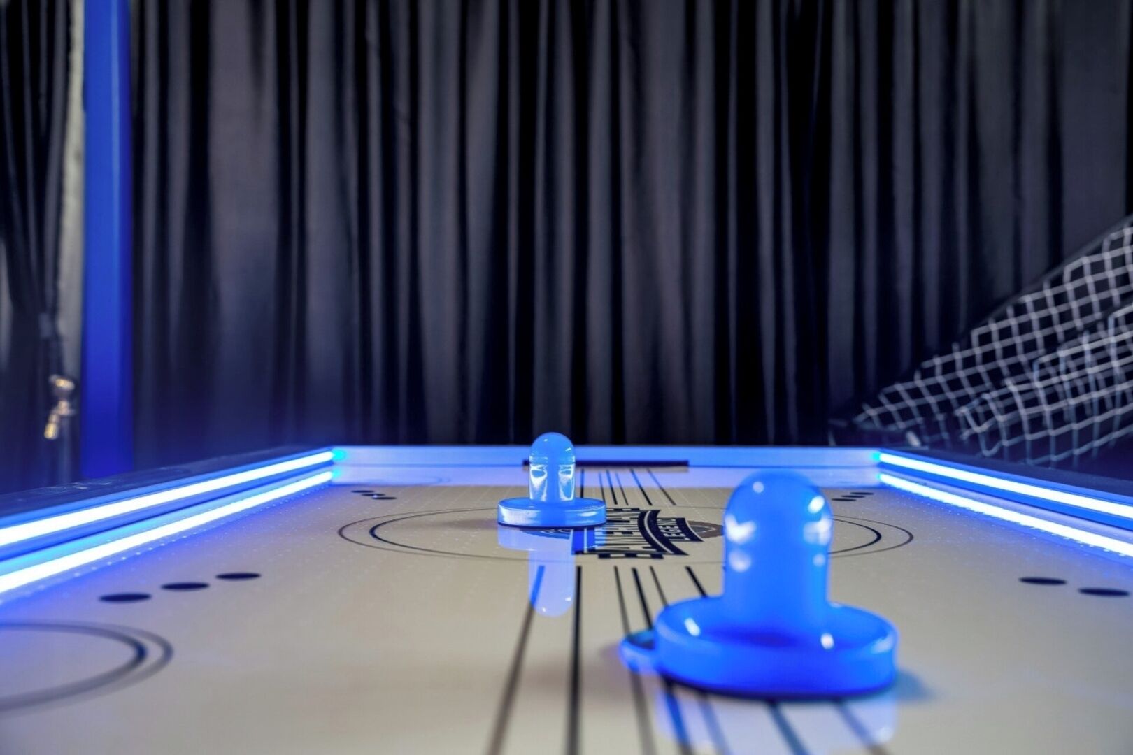 A pool table with blue lighting and a checkered tablecloth.