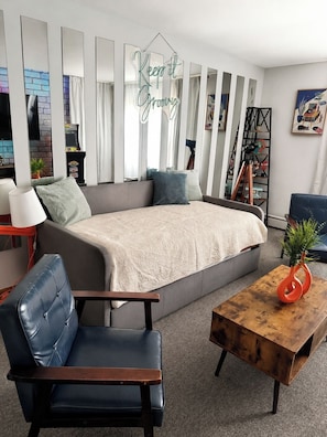 Un salon moderne comprenant un canapé, un fauteuil, une table basse et un élément décoratif.