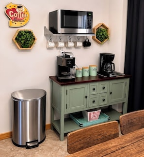 Eine Küchenzeile mit Mikrowelle, Kaffeemaschine und Aufbewahrungsbehältern.