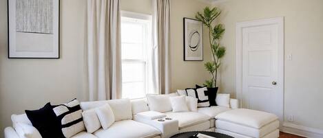 Una sala de estar moderna con un sofá modular, una mesa redonda y una puerta.