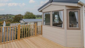 A wooden deck with a view of a village and hills in the background. - Avalon (Lyme Regis)