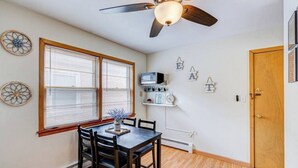 Un espace repas comprenant une table et des chaises, un ventilateur de plafond et une porte.