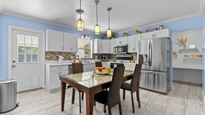 A modern kitchen with white cabinets, stainless steel appliances, and a glass dining table. - HeatedPool • HotTub • OutdoorKitchen/Theater/Games (Bradenton)