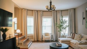 Una sala de estar moderna con sofá, mesa de centro, televisor y una escalera.
