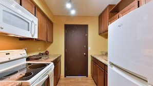 A kitchen with wooden cabinets, a white refrigerator, a stove, and a microwave.