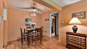 A dining area with a wooden table and chairs, a ceiling fan, and a lamp on a side table.