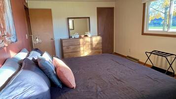 Un dormitorio con cama, cómoda, espejo y ventana.