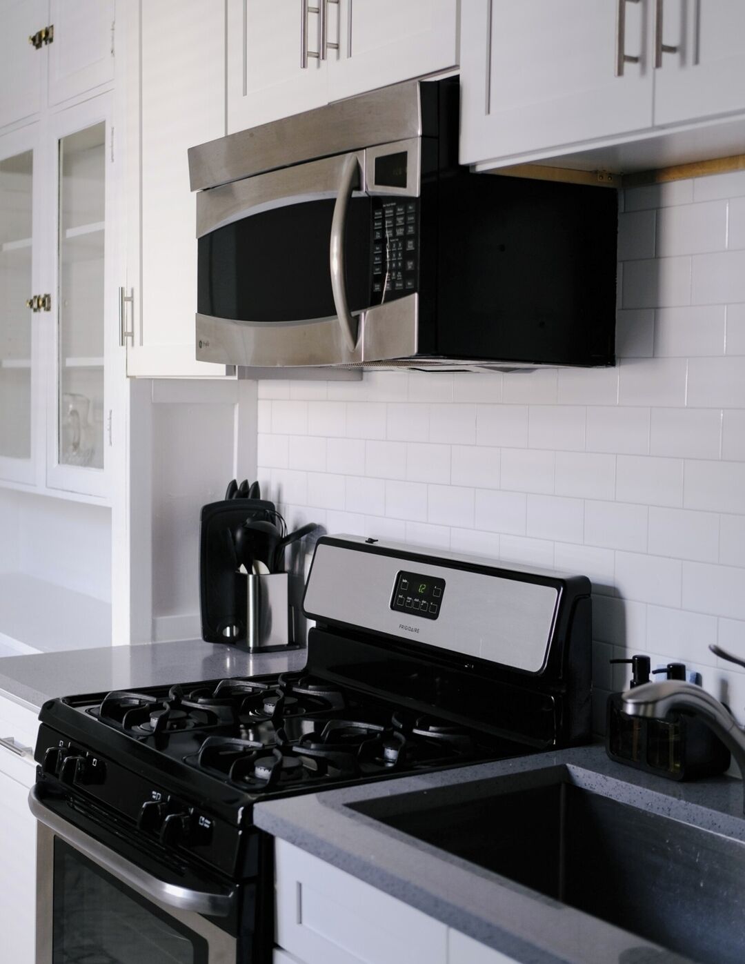 A modern kitchen with a stainless steel stove, a microwave, and white cabinets.
