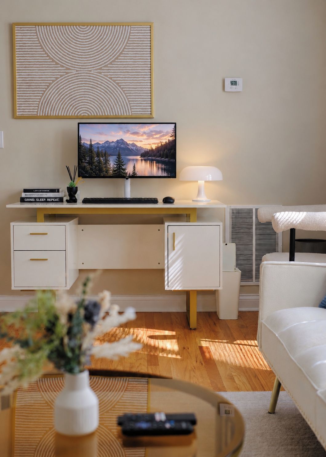 Ett modernt vardagsrum med ett skrivbord, en platt-TV, en lampa, en soffa och ett soffbord.