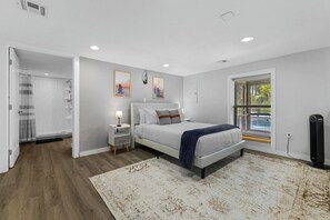 Un dormitorio con cama, mesita de noche y ventana con persianas.