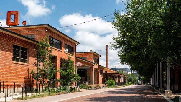A brick building with a storefront, outdoor seating, and a clear sky. - Luxury Apt Steps from Shopping & Dining, Free Parking, Resort Style Pool, Gym (San Antonio)