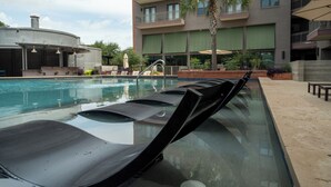 A swimming pool with lounge chairs and a building with balconies and windows in the background. - Luxury Apt Steps from Shopping & Dining, Free Parking, Resort Style Pool, Gym (San Antonio)