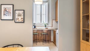 Une cuisine moderne avec des meubles en bois, un coin bar et deux œuvres d’art encadrées accrochées au mur.