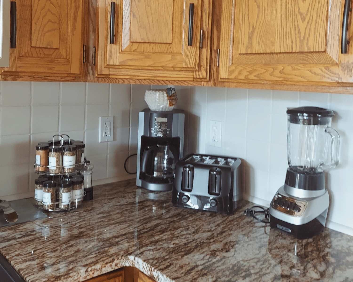 Ett kök med träskåp, en kaffebryggare, en brödrost och en mixer placerade på en bänkskiva av granit.