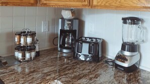 Una cucina con mobili in legno, una macchina per il caffè, un tostapane e un frullatore su un piano di lavoro in granito.