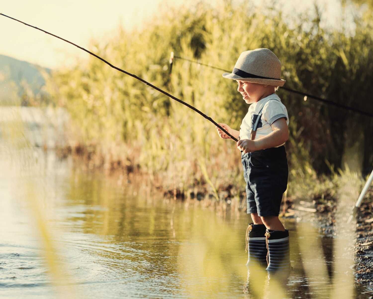 A child fishing by a calm river with greenery in the background.