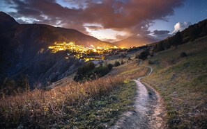 A valley with a path leading to a lit-up town nestled in the mountains. - À proximité des pistes ! Supebe studio avec balcon (Les Deux Alpes)