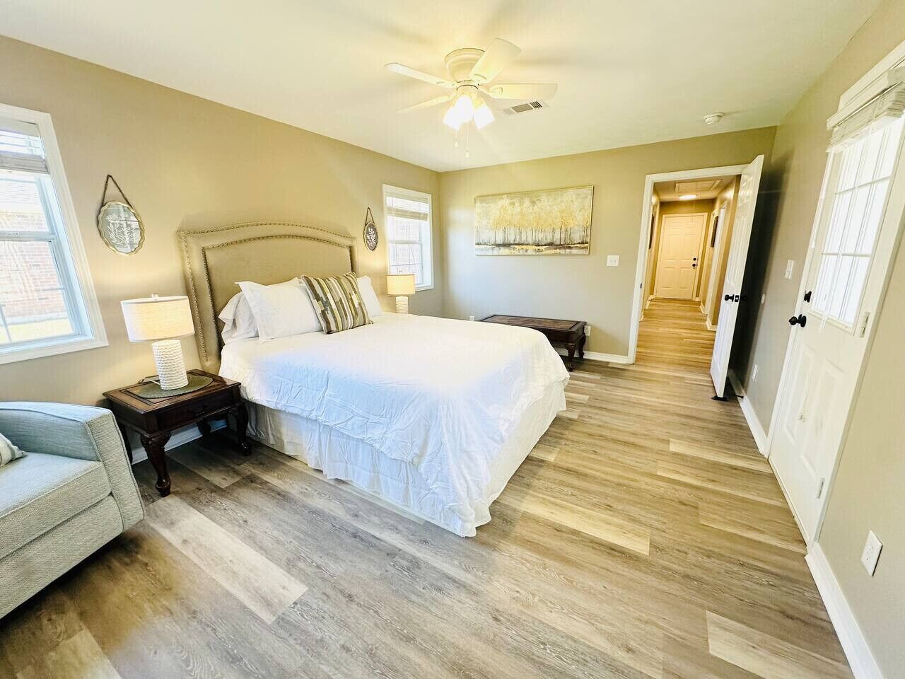 A bedroom with a large bed, a nightstand, a chair, and a ceiling fan.