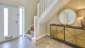 A staircase with white railings leading to a landing with a round mirror and a black and gold cabinet. - Host Stay The Sett (King's Lynn)