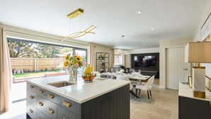 A modern kitchen with a large island, a dining area, and a TV in the background. - Host Stay The Sett (King's Lynn)