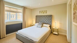 A neatly arranged bedroom with a large bed, two bedside tables, and a window with curtains. - Host Stay The Sett (King's Lynn)