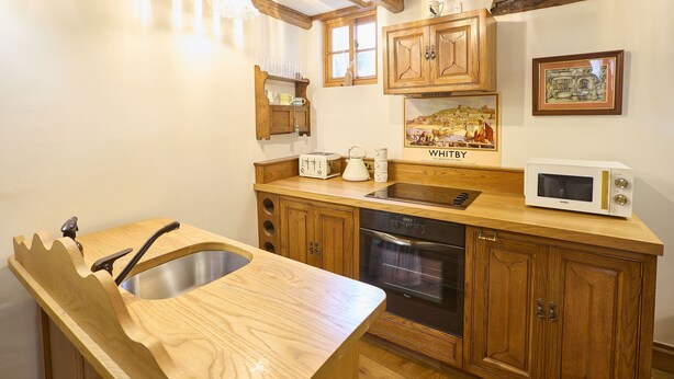 A kitchen with wooden cabinets, a stainless steel sink, a microwave, and a stove. - Host Stay The Spirit (Whitby)