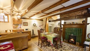 A cozy dining area with a wooden table set for four, surrounded by chairs. A fireplace with a tiled surround is visible in the background. - Host Stay The Spirit (Whitby)