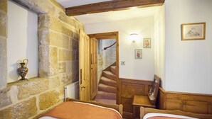 A room with two beds, a stone wall, a wooden staircase, and a small table. - Host Stay The Spirit (Whitby)