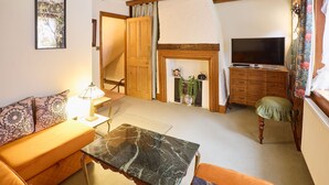 A cozy living room with a sofa, a coffee table, a fireplace, and a television. - Host Stay The Spirit (Whitby)