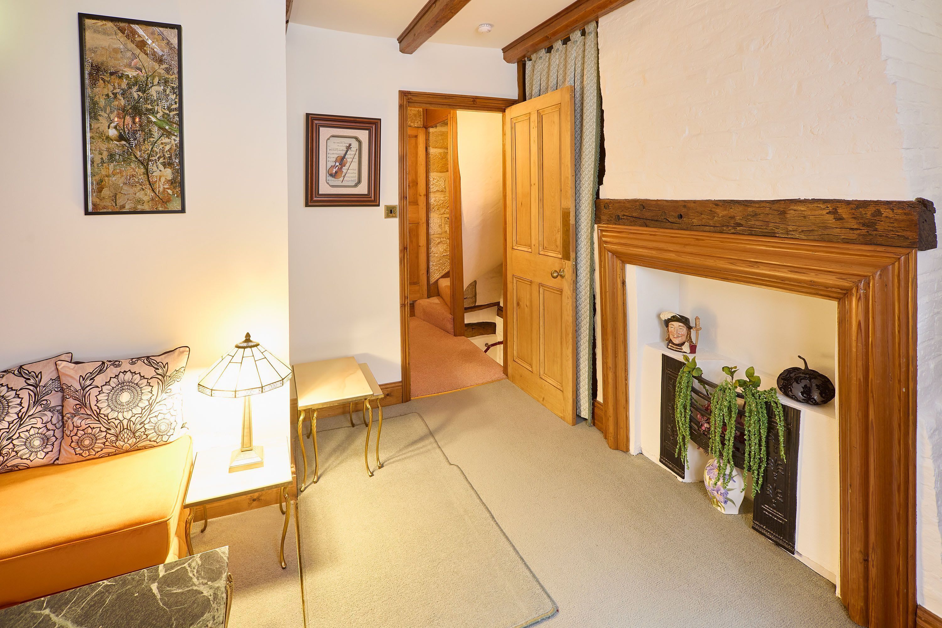 Una sala de estar acogedora con un sofá, una mesa, una lámpara, una chimenea y una escalera que lleva a otra habitación.